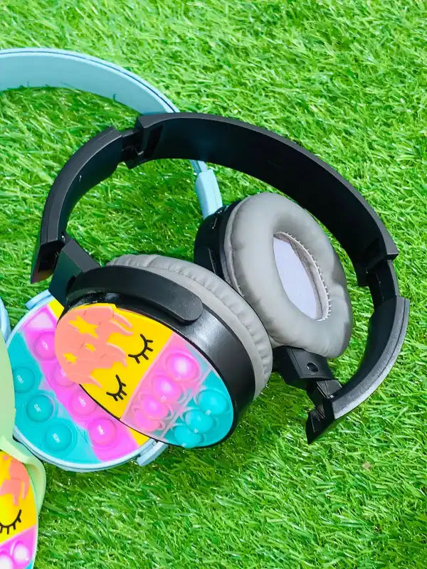 Children's headphones with a cartoon face design on a grass background