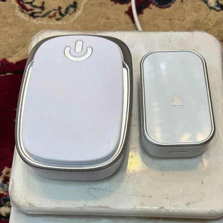 Two electronic devices on a worn surface with a patterned rug in the background.