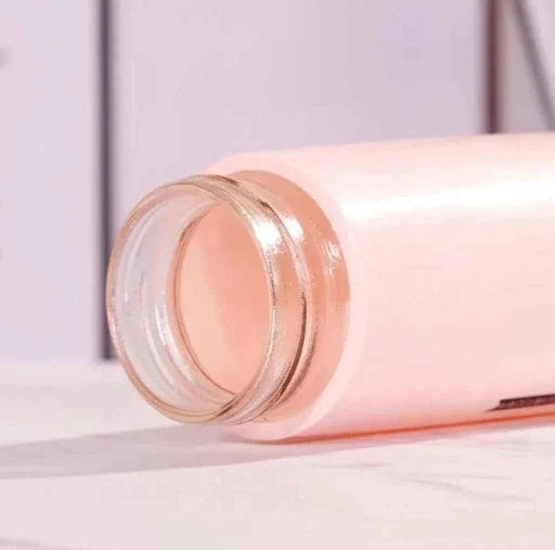 Pink glass bottle with a clear cap on a light purple background