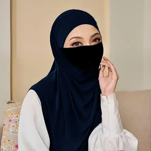 Woman wearing a navy hijab and black face covering against a beige background