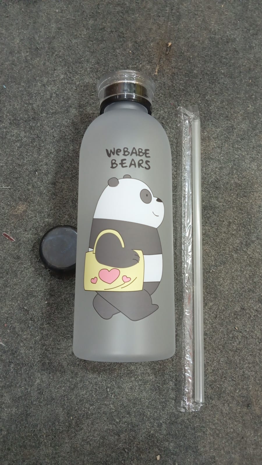 Frosted water bottle with panda design and straw on a gray surface