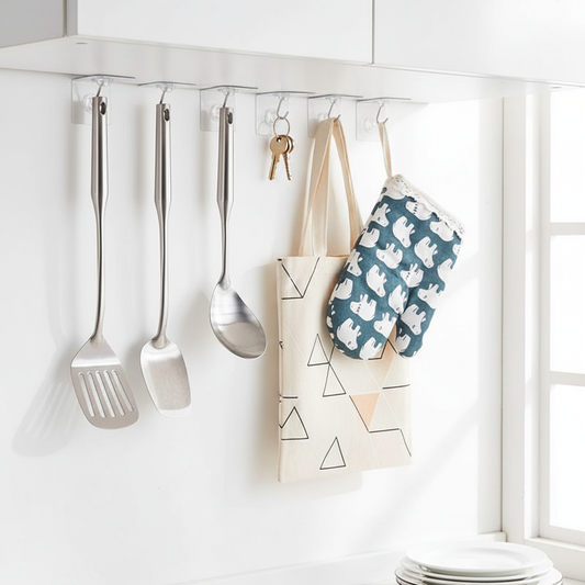 Transparent wall hooks mounted on a white kitchen wall holding utensils and keys neatly organized
