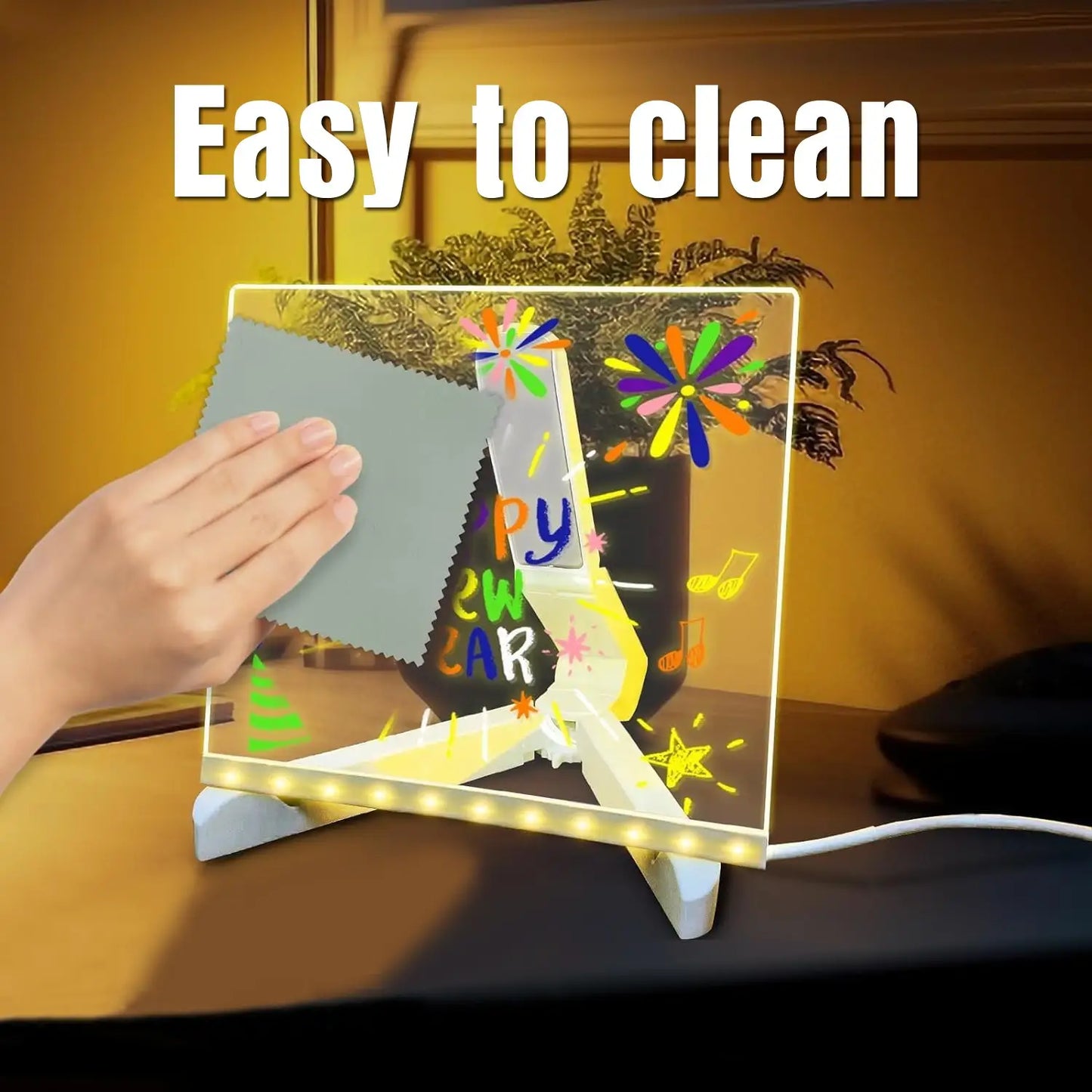 Acrylic stand with colorful drawings and text, being cleaned with a cloth, against a warm-toned background.