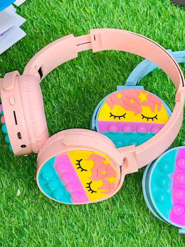 Pink children's headphones with colorful design on grass