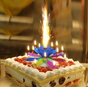 Birthday cake with lit candles and a colorful flower-shaped candle, surrounded by sparklers.