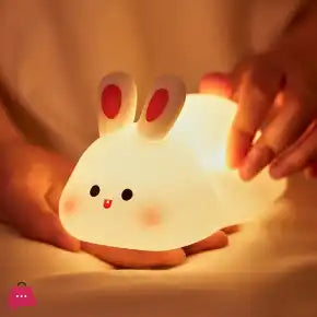 Cute rabbit-shaped night light being held by a hand with a warm glow.