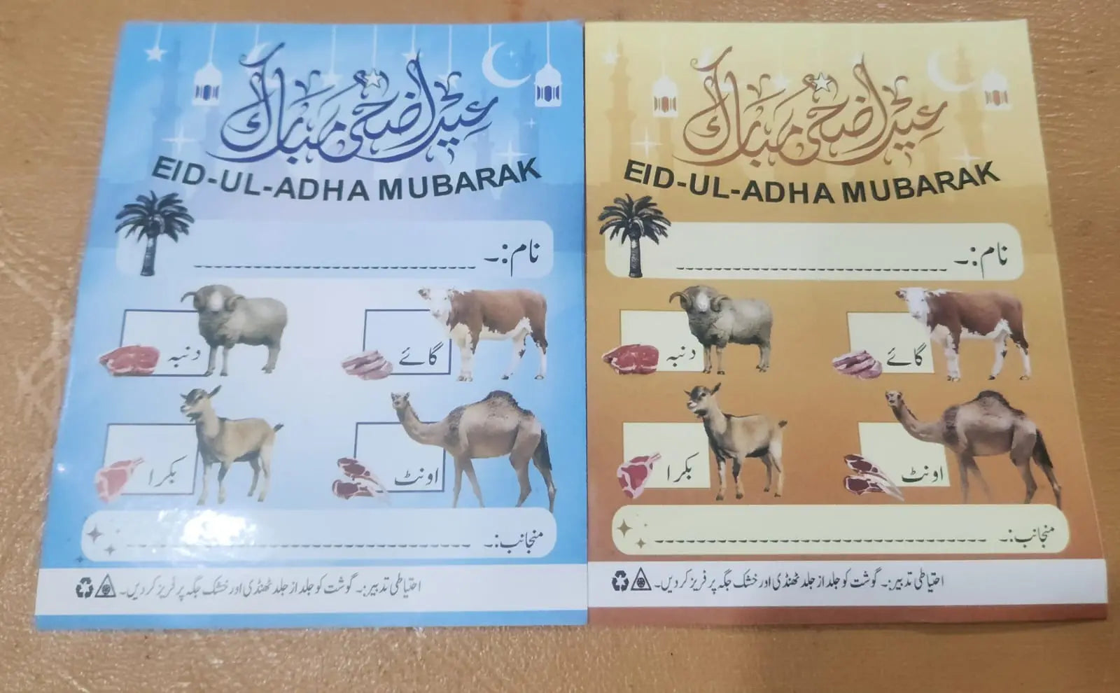 Two cards with 'Eid-ul-Adha Mubarak' text and illustrations of animals on a wooden surface.