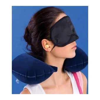 Woman wearing a black eye mask and neck pillow against a blue background