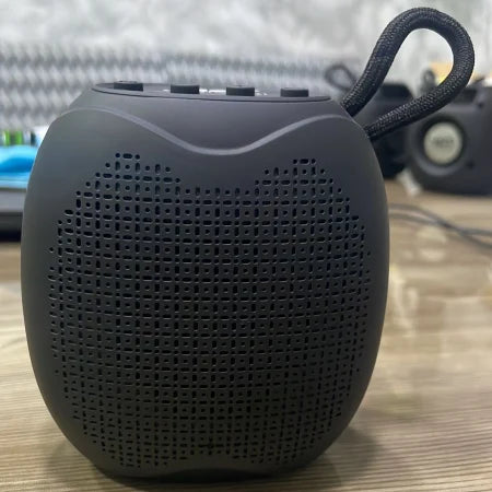 Black portable speaker on a wooden surface with a blurred background