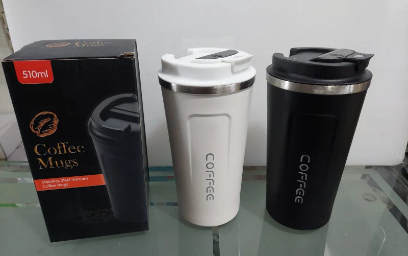 Two coffee mugs, one black and one white, with a packaging box labeled 'Coffee Mugs' on a glass surface.