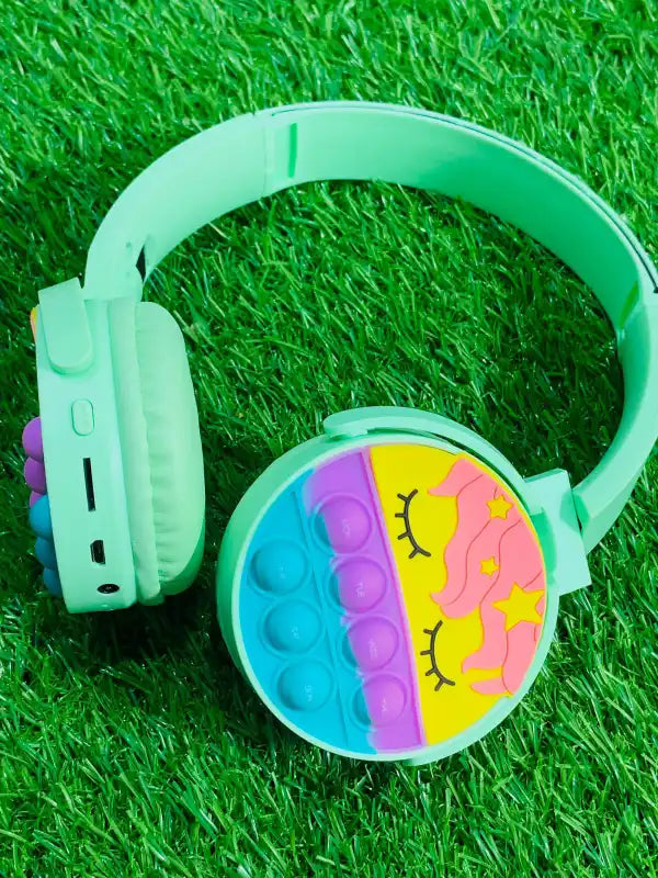 Green children's headphones with a colorful design on a grass background