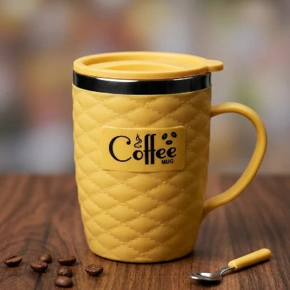 Yellow mug with lid on a wooden surface with coffee beans and a spoon.