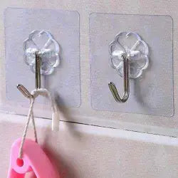 Two clear adhesive hooks on a textured wall with a pink object hanging from one of them.