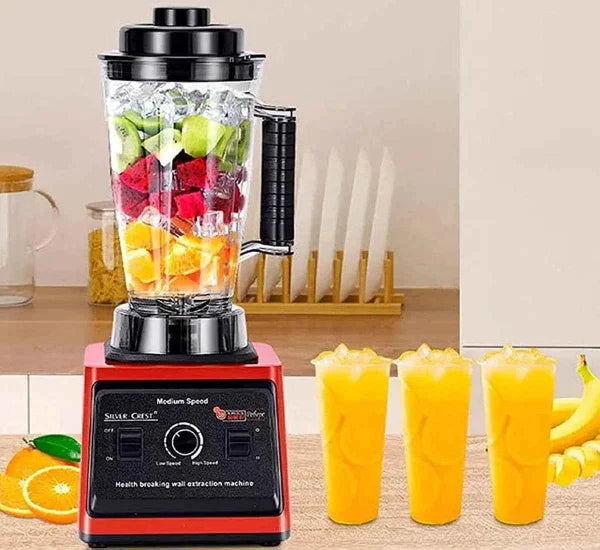 Blender with fruits and vegetables, glasses of juice, and bananas on a kitchen counter.