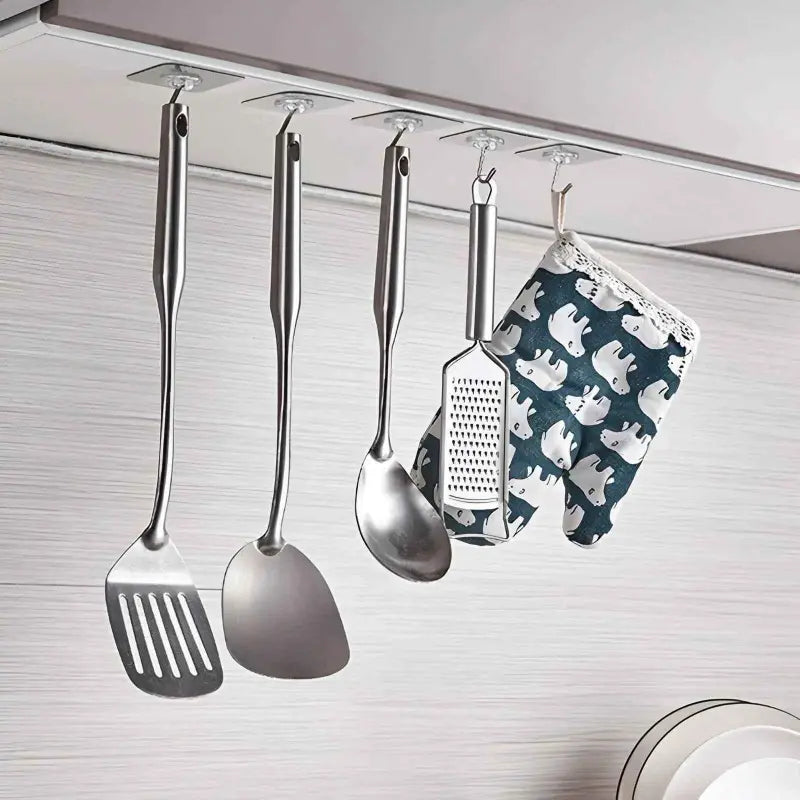 Set of kitchen utensils hanging under a cabinet with a patterned towel.