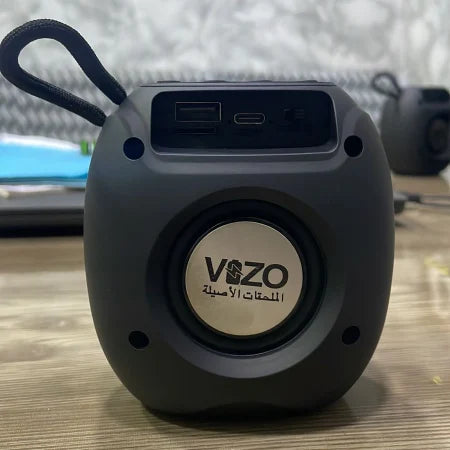 Black portable speaker with USB port on a wooden surface